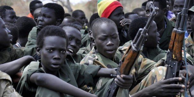 PIBOR, SOUTH SUDAN - FEBRUARY 10 : Young boys, children soldiers sit on February 10, 2015 with their rifles at a ceremony of the child soldiers disarmament, demobilization and reintegration in Pibor over sawn by UNICEF and partners. The children in Pibor, Jonglei State, surrendered their weapons and uniforms in a ceremony overseen by the South Sudan National Disarmament, Demobilization and Reintegration Commission, and the Cobra Faction and supported by UNICEF. (Photo by Samir Bol /Anadolu Agency/Getty Images)