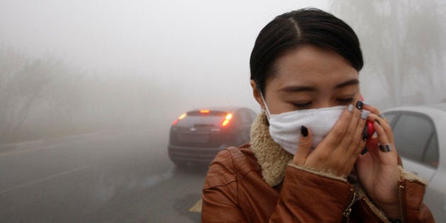 A woman wearing a mask covers her mouth with her hands as she walks in the smog in Harbin, northeast China's Heilongjiang province, on October 21, 2013. Choking clouds of pollution blanketed Harbin, which is famed for its annual ice festival, reports said, cutting visibility to 10 metres (33 feet) and underscoring the nation's environmental challenges. CHINA OUT AFP PHOTO (Photo credit should read STR/AFP/Getty Images)