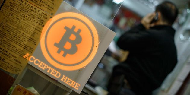 A man talks on a mobile phone in a shop displaying a bitcoin sign during the opening ceremony of the first bitcoin retail shop in Hong Kong on February 28, 2014. Bitcoin was invented in the wake of the global financial crisis by a mysterious computer guru using the pseudonym Satoshi Nakamoto and unlike other currencies, it does not have the backing of a central bank or government. AFP PHOTO / Philippe Lopez (Photo credit should read PHILIPPE LOPEZ/AFP/Getty Images)