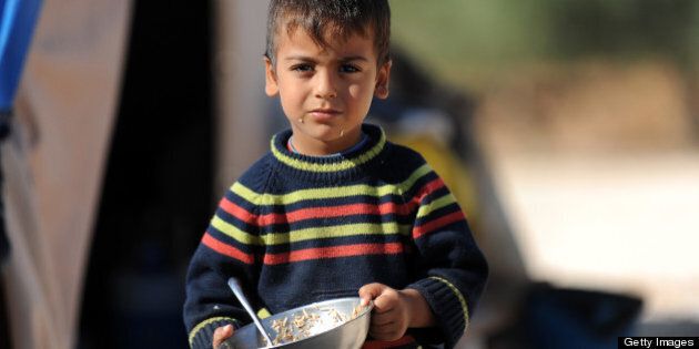 A Syrian boy looks on as he holds his plate of food in a newly built refugee camp at the village of Qah, northwestern Idlib, near the Turkish border, on October 14, 2012, which is under the control of rebel fighters. Hundreds of Syrian displaced families who were settled in a makeshift camp along the Turkish border, have been transfered to the Qah Camp, the first formal camp inside Syria, which is intended to accommodate up to 5000 refugees. AFP PHOTO/BULENT KILIC (Photo credit should read BULENT KILIC/AFP/GettyImages)