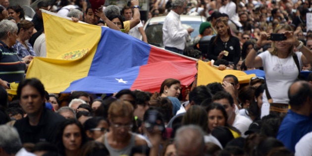 Anti-government demonstrators protest in eastern Caracas on February 27, 2014. Dueling demos of pro- and anti-government protesters have been taking to the streets since February 4 in a sign of the deep polarization of this oil-rich but economically and social troubled country, where three weeks of demonstrations have left 14 people dead, posing the greatest challenge yet to Venezuelan President Nicolas Maduro's 11-month-old government. AFP PHOTO/ JUAN BARRETO (Photo credit should read JUAN BARRETO/AFP/Getty Images)