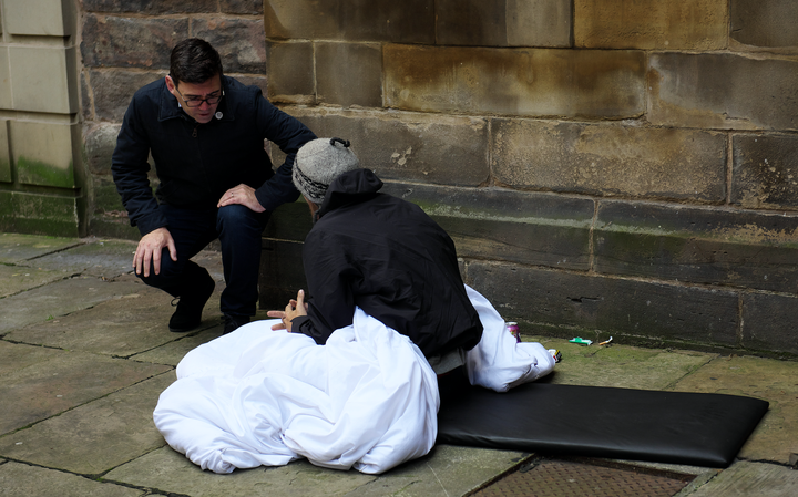 Greater Manchester Mayor Andy Burnham talking to a homeless person on the streets.