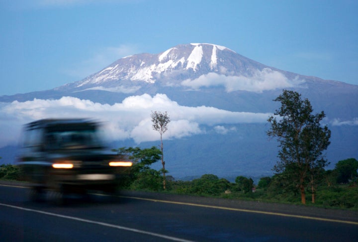 A vehicle drives past Mount Kilimanjaro in Tanzania's Hie district December 10, 2009. At the foot of Africa's snow-capped Mount Kilimanjaro, images of the mountain adorn the sides of rusting zinc shacks and beer bottle labels, but the fate of the real version hangs in the balance. REUTERS/Katrina Manson (TANZANIA ENVIRONMENT SOCIETY)