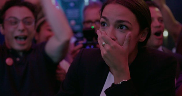 Alexandria Ocasio-Cortez com cara de surpresa ao vencer as primárias do Partido Democrata em 2018,...