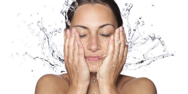 Beautiful wet woman face with water drop. Close-up portrait on white background