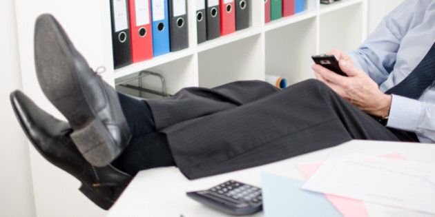 Relaxed businessman using his smartphone at office