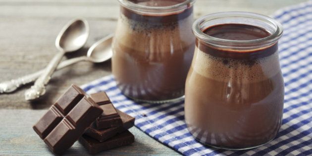 Chocolate dessert panna cotta in glass jars on wooden background