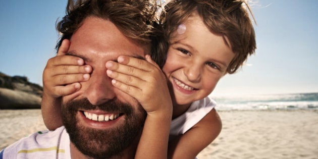 Boy (4-5) with hand over fathers eyes, close up