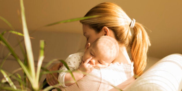 Mother comforts baby boy. They are in bedroom.