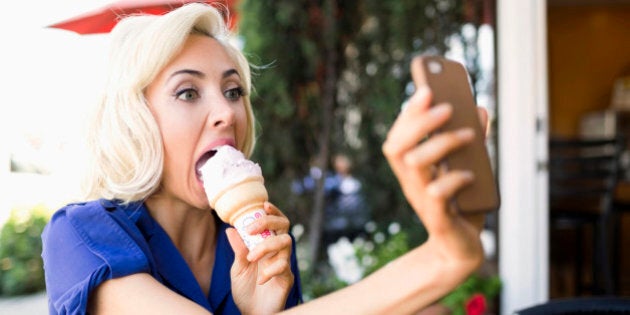 USA, California, Costa Mesa, Woman photographing herself with ice-cream