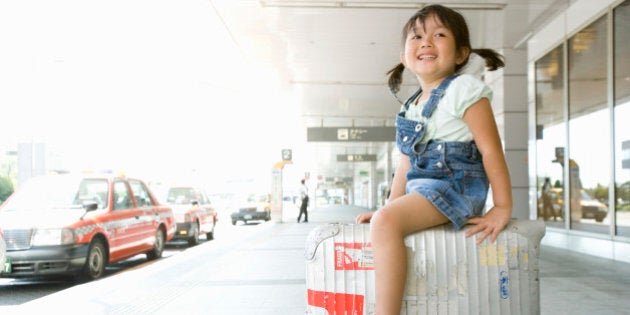 A girl rides suitcase by cabstand in airport