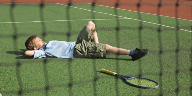 Boy lying on tennis court