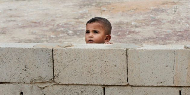 A Syrian boy peeks from behind a wall near a mobile clinic at a refugee camp in the southern town of Zahrani, south of the port city of Sidon, Lebanon, Monday, Sept. 7, 2015. There are some 1.2 million registered Syrian refugees in Lebanon, many of them living in flimsy tents scattered across the country. (AP Photo/Bilal Hussein)