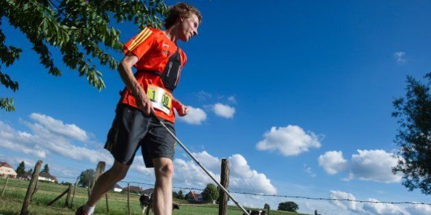 Clement Gass, who is nearly blind, runs the 26 km 'trail of Kochersberg' with a white cane and a GPS device using voice navigation in Quatzenheim, eastern France, on June 13, 2015. Gass, 27, ran the trail along with 219 other participants without the assistance of another athlete. AFP PHOTO / SEBASTIEN BOZON (Photo credit should read SEBASTIEN BOZON/AFP/Getty Images)