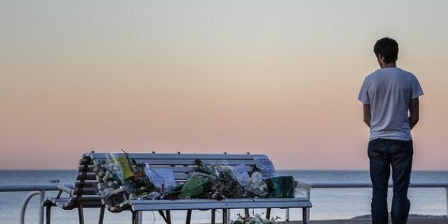 A man looks at a tribute laying on a bench near where a person was killed on the Promenade des Anglais on July 17, 2016.