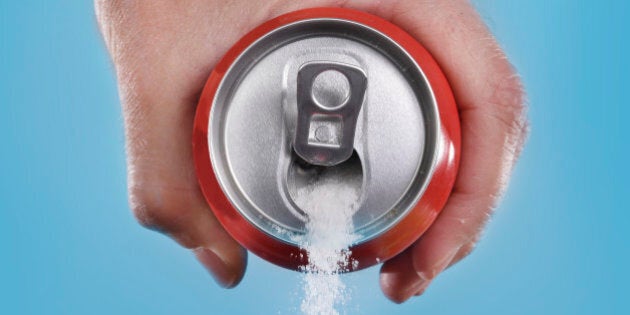 hand holding soda can pouring a crazy amount of sugar in metaphor of sugar content of a refresh drink isolated on blue background in healthy nutrition, diet and sweet addiction concept