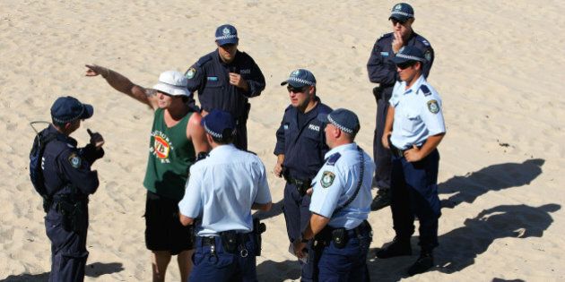 Police question a man on Cronulla Beach in Sydney, Australia, Sunday, Dec. 18, 2005. Cronulla is one of a number of Sydney beaches that is experiencing a high volume of police patrols, the largest security operation since the Olympics, following a week of racial unrest. (AP Photo/Paul Miller)