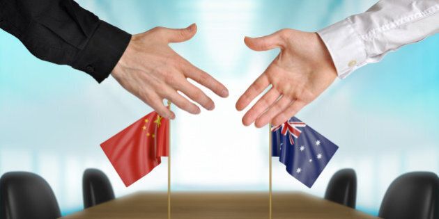 Two diplomats from China and Australia extending their hands for a handshake on an agreement between the countries.