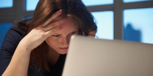 Stressed Caucasian businesswoman using laptop in office