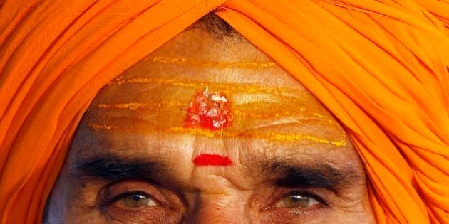 A Sadhu, or Hindu holy man, his face smeared with turmeric and vermilion paste, looks on at the Sangam, the confluence of rivers Ganges, Yamuna and mythical Saraswati, in Allahabad, India, Thursday, Oct. 28, 2010. (AP Photo/Rajesh Kumar Singh)