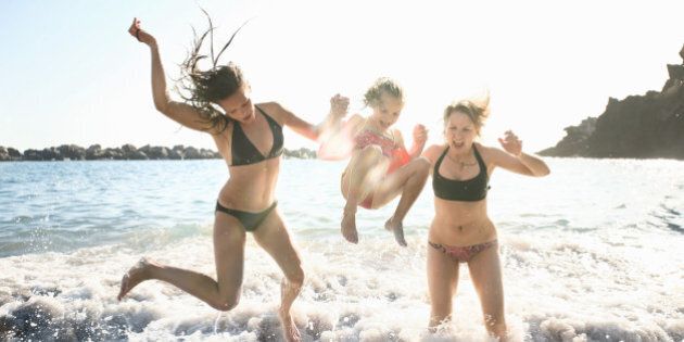 Three girls jumping on wave in ocean