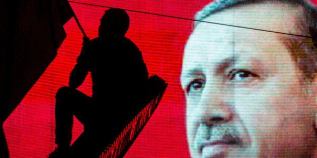 ANKARA, TURKEY - JULY 18: A supporter of Turkish President Recep Tayyip Erdogan waves a flag against an electronic billboard during a rally in Kizilay Square on July 18, 2016 in Ankara, Turkey. Clean up operations are continuing in the aftermath of Friday's failed military coup attempt. Latest figures according to Turkey's Prime Minister Binali Yildirim raises the death toll to 208 with 1491 wounded. Continuing raids across the country have seen 7543 people detained and 316 arrested including high ranking soldiers, judges and police officers. (Photo by Chris McGrath/Getty Images)