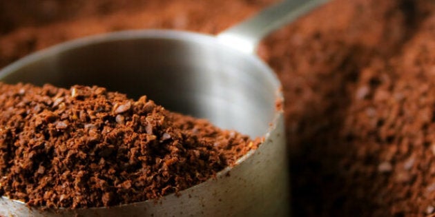 Fresh aroma of coffee grounds in stainless steel scoop.