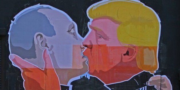 TOPSHOT - People walk past a mural on a restaurant wall depicting US Presidential hopeful Donald Trump and Russian President Vladimir Putin greeting each other with a kiss in the Lithuanian capital Vilnius on May 13, 2016.Kestutis Girnius, associate professor of the Institute of International Relations and Political Science in Vilnius university, told AFP -This graffiti expresses the fear of some Lithuanians that Donald Trump is likely to kowtow to Vladimir Putin and be indifferent to Lithuanias security concerns. Trump has notoriously stated that Putin is a strong leader, and that NATO is obsolete and expensive. / AFP / Petras Malukas (Photo credit should read PETRAS MALUKAS/AFP/Getty Images)
