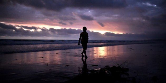 A young boy walks at sunset on the beach of Kerema, papua New Guinea, on September 9, 2014. AFP PHOTO / ARIS MESSINIS (Photo credit should read ARIS MESSINIS/AFP/Getty Images)