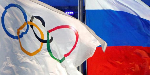 The Russian national flag (R) and the Olympic flag are seen during the closing ceremony for the 2014 Sochi Winter Olympics, Russia, February 23, 2014. REUTERS/Jim Young/File Photo