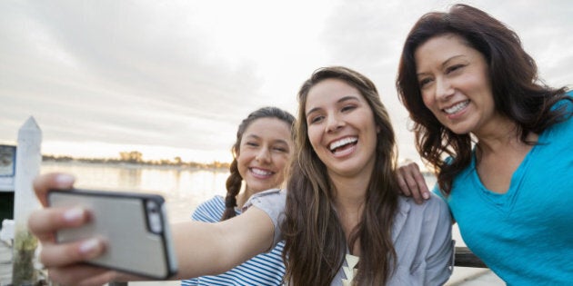 Smiling mother and daughters taking self portrait with smartphone