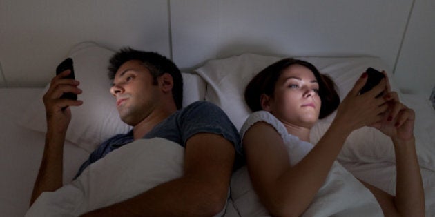 Young couple with smartphones in their bed