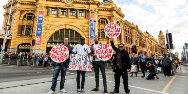 Protestors holding 'Stop racism now' placards stand in front of Flinders Street station during a rally protesting against the forced closure of Aboriginal Communities in Australia