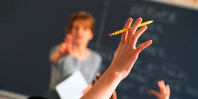 Teacher pointing to raised hands in classroom