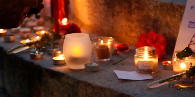 A woman lights a candle to place with flowers and candles at the town hall in Saint-Etienne-du-Rouvray, near Rouen in Normandy, France.