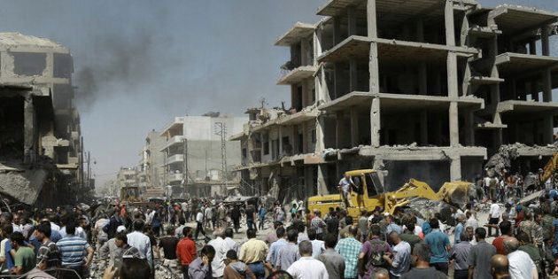 Syrians gather at the site of a bomb attack in Syria's northeastern city of Qamishli.