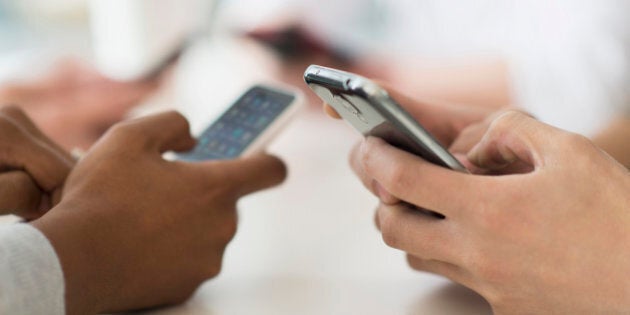 Close up of friends texting with cell phones at table