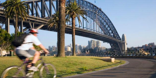 Australia, New South Wales, Sydney. An early morning cyclist rounds Daves Point Reserve at the foot of the Harbour Bridge on Sydney Cove