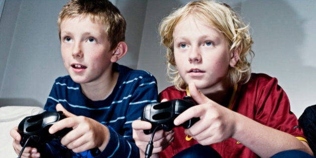 two boys aged 10 and 13 playing with games consoles.