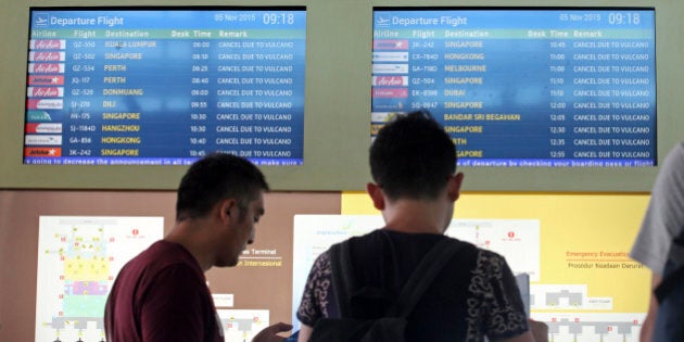 Passengers look at a flight information monitor with canceled flights at Ngurah Rai International Airport in Bali, Indonesia, Thursday, Nov. 5, 2015. Thousands of tourists are stranded on three Indonesian islands after ash from the Mount Rinjani volcano forced the closure of airports and blanketed villages and farmlands. (AP Photo/Firdia Lisnawati)