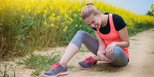 Young runner having an accident outside in spring canola field