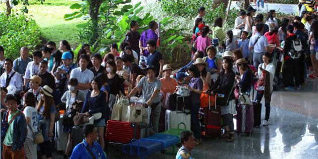 Passengers line up after their flights were canceled at Bali's international airport, in Denpasar, Indonesia, Friday, July 10, 2015. Ash spewing from a volcano on Indonesia's main island of Java has sparked chaos for holidaymakers as airports close and international airlines cancel flights to tourist hotspot Bali, stranding thousands. (AP Photo/Firdia Lisnawati)