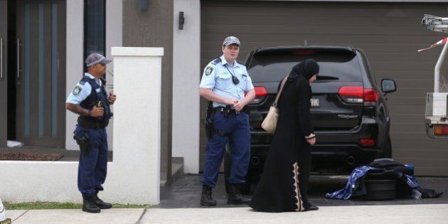 Police talk to a woman outside a property in the suburb of Merrylands in Sydney, Wednesday, Oct. 7, 2015. Police arrested four people during a series of raids Wednesday in connection with the slaying of a civilian police worker, which officials have said they believe was linked to terrorism. (AP Photo/Rick Rycroft)