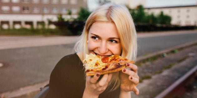 Friends sitting together outdoors sharing a pizza