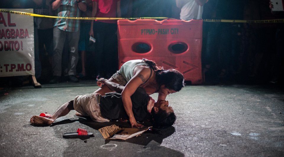 Jennelyn Olaires, 26, cradles the body of her partner, who was killed and left with a sign proclaiming he was a drug dealer. She disputes it.