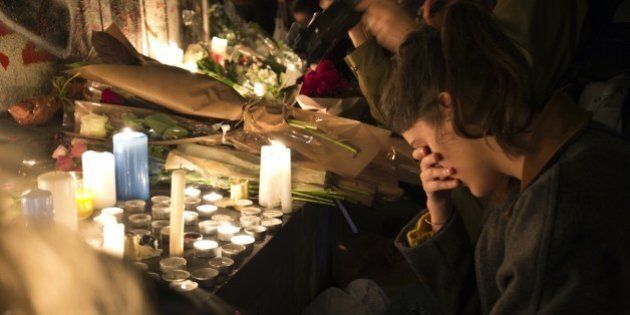 A woman reacts in front of candles in tribute to the victims of the deadly Paris' attacks on November 14, 2015 at the Place de la Republique in Paris. Islamic State jihadists claimed a series of coordinated attacks by gunmen and suicide bombers in Paris on November 13 that killed at least 129 people in scenes of carnage at a concert hall, restaurants and the national stadium. AFP PHOTO / JOEL SAGET (Photo credit should read JOEL SAGET/AFP/Getty Images)