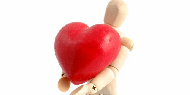 A wooden mannequin holds a symbolic heart.