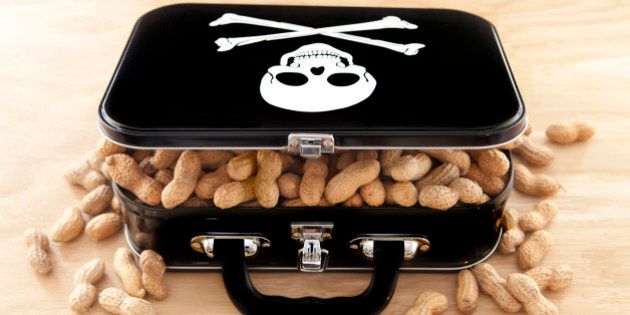 Black lunchbox with skull and crossbones on lid and peanuts overflowing out of container