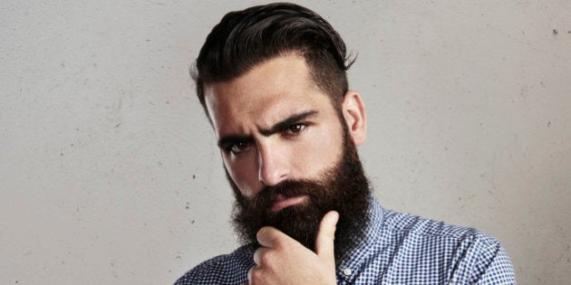 Portrait of thoughtful bearded man on concrete wall background