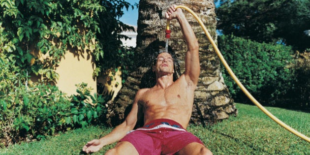 Man Leaning Against a Tree, Holding a Hose Above his Head